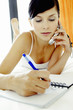 A lady lying on the bed taking messages while talking on the hand phone