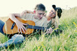 A guy playing a song on his guitar for his girlfriend