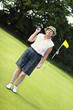 An old lady in golf attire standing in a golf course
