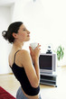 A woman in black spaghetti top holding a cup in the living room