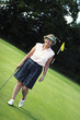 An old lady in golf attire standing in a golf course 