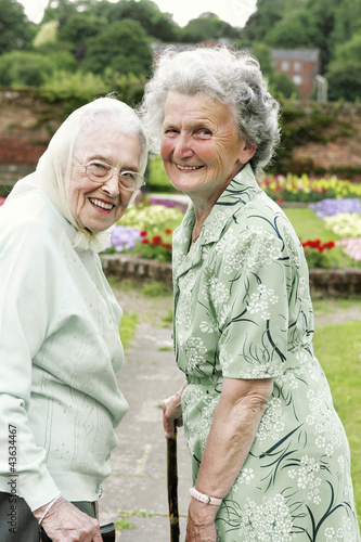 Photo: Two old women with walking sticks walking in the park Two old women with walking sticks walking in the park
