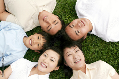 Photo: Top angle view of a family lying on the grass in circle Top angle view of a family lying on the grass in circle