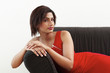 A lady in red toga dress lying on a black couch