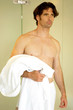 A shirtless man in boxer shorts holding a bathrobe