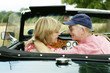 An old couple sitting in a roofless car 