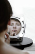 Mirror reflection of a woman applying lip liner 