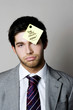 Businessman with a phone message sticking on his forehead