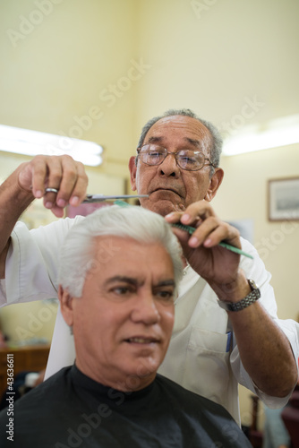 Photo: Old barber cutting hair to client in barber shop Old barber cutting hair to client in barber shop