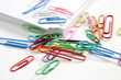 Colourful paper clips and a stack of papers