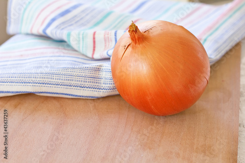 Photo: An onion and kitchen towel on wooden board An onion and kitchen towel on wooden board