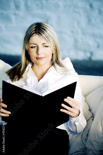 Photo: A business lady reading on a couch A business lady reading on a couch