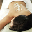 Woman lying on a massage table with rose petals on her back