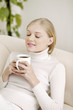 Young woman sitting on the couch enjoying a cup of coffee