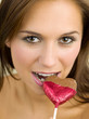 Woman biting a heart-shaped chocolate