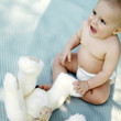 Baby boy sitting on the picnic mat with his teddy bear