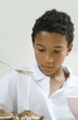 Boy pouring flour mixture on cupcakes