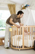 Man playing with baby in a crib