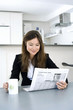 Businesswoman reading newspaper while having coffee