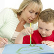 Boy drawing, woman watching