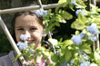 Girl looking through wooden post with flowers