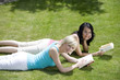 Photo: Two women lying forward in the park reading books Two women lying forward in the park reading books