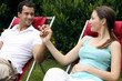 Man and woman holding hands while sitting on garden chairs