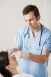 Male doctor pressing a disposable thermometer on patient's forehead
