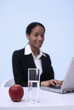 Photo: Businesswoman using laptop, focus on the apple and glass of water Businesswoman using laptop, focus on the apple and glass of water