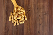 Peanuts in a wooden spoon on brown wooden background