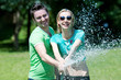 Young man and woman playing with water spray