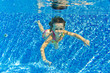 Happy smiling underwater child in swimming pool, summer vacation