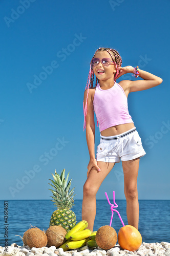 Photo: Little girl with fruit on the beach Little girl with fruit on the beach