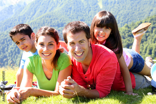 Photo: Portrait of happy family laying on the grass in mountain Portrait of happy family laying on the grass in mountain