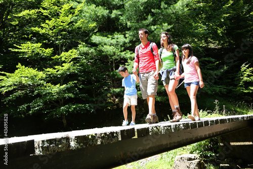 Photo: Family walking on a bridge in mountain forest Family walking on a bridge in mountain forest