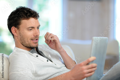 Photo: Man in sofa using electronic tablet Man in sofa using electronic tablet