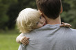 Closeup portrait of young toddler baby boy resting on daddy's sh