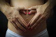 Cuore con le mani su pancia di mamma in attesa
