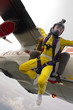 Two girls jump out of an airplane.