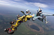 Five skydivers free-fall in the figure.