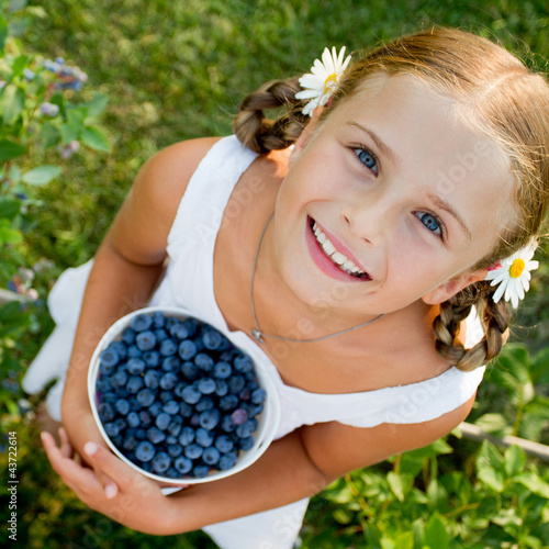 Photo: Lovely girl with fresh blueberries in the garden Lovely girl with fresh blueberries in the garden