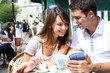 Couple on a coffee shop terrace reading tourist book