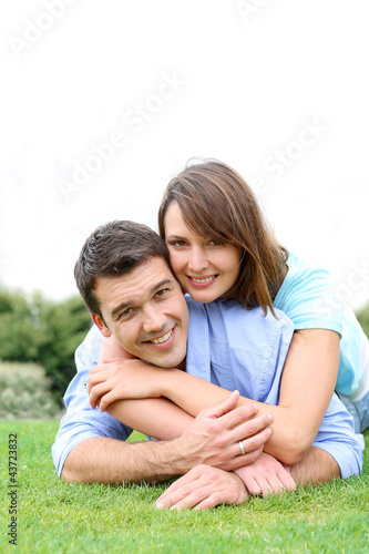 Photo: In love couple laying in public park In love couple laying in public park