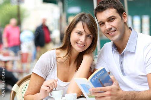 Foto: Couple on a coffee shop terrace reading tourist book Couple on a coffee shop terrace reading tourist book