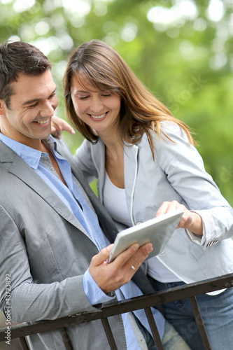 Photo: Couple standing in park with electronic tablet Couple standing in park with electronic tablet