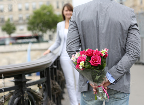 Photo: Man ready to give flowers to girlfriend on a bridge Man ready to give flowers to girlfriend on a bridge