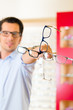 Junger Mann beim Optiker oder Brillengeschäft
