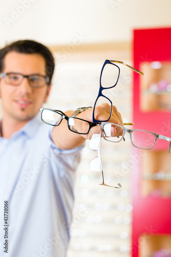 Foto: Junger Mann beim Optiker oder Brillengeschäft Junger Mann beim Optiker oder Brillengeschäft