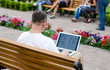 Foto: Man using a laptop in a public park Man using a laptop in a public park