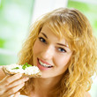 Foto: Portrait of young happy woman eating crispbread Portrait of young happy woman eating crispbread